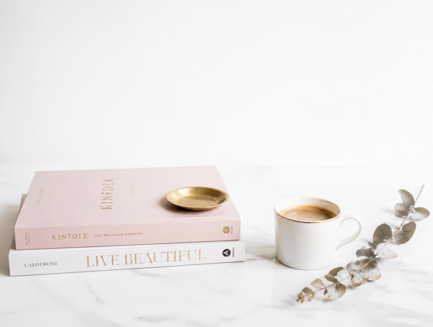 Libros apilados junto a una taza de café sobre mármol blanco